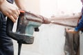 Builder worker man with hammer drill perforator equipment making hole in gray wall construction Royalty Free Stock Photo