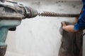 Builder worker man with hammer drill perforator equipment making hole in gray wall construction Royalty Free Stock Photo