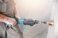 Builder worker pneumatic hammer drills hole in concrete brick wall with diamond crown for electric cable, socket, switch