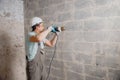 Builder worker pneumatic hammer drills hole in concrete brick wall with diamond crown for electric cable, socket, switch