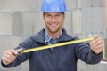 Builder worker shows measures tape