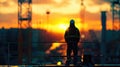 Builder worker silhouette in a work helme standing on a construction site, against a sunset Royalty Free Stock Photo