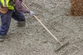 Builder worker standing in fresh cement, using a metal rake to f Royalty Free Stock Photo