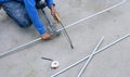 Builder worker using hacksaw to cutting conduit pipes on concrete floor for interior electrical installation work Royalty Free Stock Photo