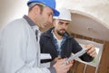 builders with clipboard and electrical panel indoors Royalty Free Stock Photo