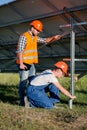 Builders installing frame with solar panels on helical pile. Royalty Free Stock Photo