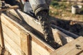 Builders pouring concrete with pump truck in wooden formwork with reinforcement. Workers pouring concrete in formwork for