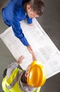 Builders shake hands over blueprint