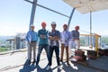 Builders Team Leader With Group Of Apprentices At Construction Site Over City View Background, Happy Smiling Engineers