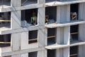 Builders are working on a construction site, assembling the frame of a high-rise building from rebar, cement blocks