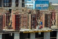 Builders are working on a construction site, assembling the frame of a high-rise building from rebar, cement blocks and others