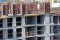 Builders are working on a construction site, assembling the frame of a high-rise building from rebar, cement blocks and others