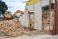 Building being demolished by an excavator