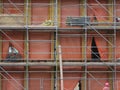 Building being renovated covered with orange colored plastic and scaffolds