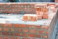 Building a brick foundation wall corner of a house construction using spirit level to keep the brickwork upright and level on a Royalty Free Stock Photo