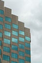 Building for business with rigid geometric design or shape with blue windows and zig zag angles with gray sky background