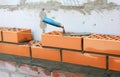 Building a cavity wall from concrete blocks and red facing bricks. An external masonry cavity wall bricklaying using a level