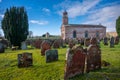 Building and cemetery stones of Kirkandrews under the blue sky with clouds in Carlisle