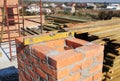 Building a chimney out of masonry, noncombustible red bricks and cement on the rooftop of a house