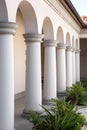 A building with columns and arched openings at the building with flowerbeds.