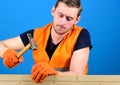 Building and construction concept. Man, labourer, handyman in bright vest and protective gloves handcrafting, blue Royalty Free Stock Photo