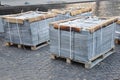 Building and construction materials, stone and concrete pavers (paving stone) or patio blocks organized on pallets.