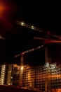 Building construction site with cranes and light flare at night time background Royalty Free Stock Photo