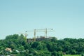 Building construction site with cranes and scaffold in the park for hotel or school college