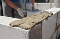 A building contractor is applying a generous amount of mortar with a spade mortar to bricklaying a wall of a new house Royalty Free Stock Photo