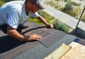 A building contractor is installing asphalt shingles over roofing underlayment and flashing on