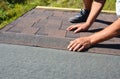 A building contractor is installing  dimensional asphalt roof shingles on the underlayment of the house construction repairing the Royalty Free Stock Photo