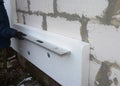 A building contractor installing external wall polystyrene boards insulation using plastic capped fixings is checking if the wall