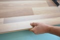 A building contractor is installing wood laminate flooring on underlayment