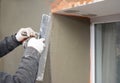 Building contractor plastering wall with fiberglass mesh, stucco, plaster mesh after rigid insulation