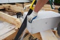 A building contractor in protective gloves is cutting an autoclaved aerated concrete block using a hand saw Royalty Free Stock Photo