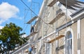 Building contractors on scaffoldings are applying stucco finish, coating and plastering the facade wall of the house