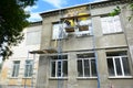 Building contractors on scaffoldings are plastering, rendering the facade of a building using plastic and fiberglass mesh as a