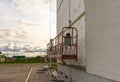 Building cradle on the renovated house wall. Facade insulation with foam in Russia. Decorative plaster