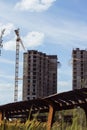 Building cranes at front of a multi-storey uilding under construction, new house for many families