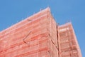 Building facade corner under construction is covered with a protective construction mesh. Building under construction wrapped with Royalty Free Stock Photo