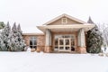 Building facade framed with lush snowy evergreens against cloudy sky in winter