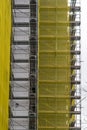 Building facade renovation, old house reconstruction, repair. Scaffold in front of building facade covered with yellow transparent Royalty Free Stock Photo