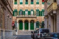Building facade with traditional Maltese green window shutters in Sliema, Malta