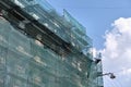 Building facade under renovation works with construction scaffolding frame covered with protective net for workers Royalty Free Stock Photo