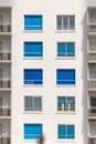 Building facade with windows with blue rolling shutters Royalty Free Stock Photo