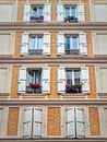 Building facade with yellow painted walls of brick masonry and windows with white outdoors louvers Royalty Free Stock Photo