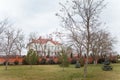 Building and front yard with fence, lawn, autumn trees and small firs