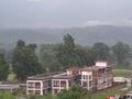 BUILDING IN INDIA SURROUNDED GREEN TREES MOUNTAINS AND HILL.