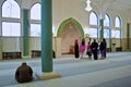 Building interior of a mosque. Arabic Muslim man reading Koran and praying