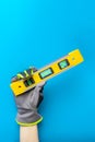 Building level. Hand in gloves holds a yellow building level on a blue background. Postcard or poster for print, place Royalty Free Stock Photo